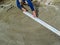 The builder smooths the surface of a dry sand-cement mortar with a long metal plank for laying paving slabs on the site. Male