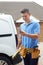 Builder With Van Checking Text Messages On Mobile Phone Outside