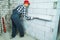 Builder in work wear checking evenness of block wall with construction ruler