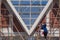 builder worker on wooden scaffolding is painting white color on gable roofs structure at house construction site