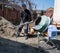 Builder works with concrete mixer. Construction worker with shovel in hand