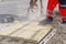 Builders cutting concrete tactile flags with a petrol power saw and placing them on concrete during pedestrian road crossing