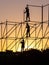 Builders are dismantling the tubular structure. Against the backdrop of the setting sky, only silhouettes are visible.
