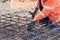 Builders hands fixing steel reinforcement bars at construction site. Steel fixer assembling reinforcement cage. Selective focus