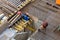 Builders in orange helmets make a steel reinforcement cage for pouring a concrete slab. Steel rods and metal formwork on