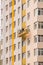 Builders paint the facade of a high-rise residential building