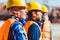 Builders in reflective vests and hardhats standing together at construction site, looking