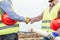 Builders shaking hands making an agreement on costruction site - Workers reaching a deal on renewable energy project