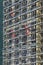 Builders team in red uniform work outdoors on scaffolding covering facade of new residential apartment  building.