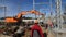 Builders walk past excavator at construction site of station