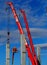 Building activity. Two telescopic cranes and a cherry pickers install the first concrete structural columns for a new construction