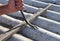 A building contractor is removing nails from the asbestos rooftop with a wrecking bar renovating the house roof