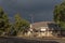 Building in De Rust against backdrop of dark clouds