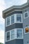 Building facade with gray wooden building with slatted wood and white accent paint around the windows with flat roof