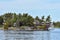 Building in a grassy area on the coast of a lake during daytime, and surrounded by trees. Yacht parked in the lakeside harbor.