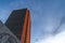 Building with gray and orange exterior wall viewed from below against cloudy sky