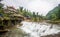 Building inside river and mountain under cloudy sky