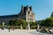 Building of the Louvre museum and tourists at the fountain in The Jardin Des Tuileries Paris,  a public garden located between the