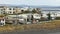 Building and parked cars in outskirts of small icelandic town, river and mountains are in background