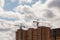 building process of large residential apartment building with crane on cloudy sky background