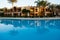 Building reflection on swimming pool water. Evening sun on building with two palms reflect to water mirror.