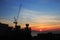 Building silhouettes and Industrial construction cranes on beautiful sunset