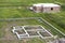 Building site in green field. Trenches dug in ground and filled with cement as foundation for future house and brick basement floo