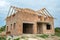 Building site with unfinished brick house with wooden roofing frame for future roof under construction