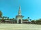 Building spire in a tropical, hot country. white, high, sharp spire on the roof. building with a tower on top. near palm trees and