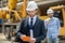 Building supervisor checking something on tablet, foreman standing behind him with coffee cup