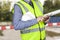 Building surveyor in hi vis with site plans checking his smart phone