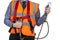 Building Surveyor in orange visibility vest securing safety harness lanyard