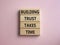 Building Trust takes Time symbol. Wooden blocks with words Building Trust takes Time. Beautiful pink background. Business and