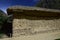 A building with walls of stones and clay and a roof of straw on the territory Inca ruins of Ollantaytambo, Peru.