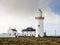 Buildings and Loop head Lighthouse in county Clare, Ireland. Popular travel landmark and sightseeing area. Cloudy sky. Irish