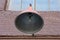 Bulb in a large open circular lampshade of metal on a brick wall