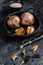 Bulbs of fermented black garlic in a pan. Black background. Top view