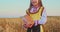 Bulgarian girl in ethnic folklore embroidery traditional costume with homemade bread in wheat Bulgaria