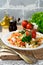 Bulgur with roasted peppers, tomatoes, parsley and feta cheese on a wooden background. Vegetarian dish. Selective focus