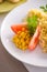 Bulgur with vegetables and rolls of baked fish with corn, tomatoes and lemon on a white plate
