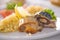 Bulgur with vegetables and rolls of baked fish with corn, tomatoes and lemon on a white plate