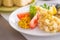 Bulgur with vegetables and rolls of baked fish with corn, tomatoes and lemon on a white plate