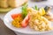 Bulgur with vegetables and rolls of baked fish with corn, tomatoes and lemon on a white plate