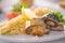 Bulgur with vegetables and rolls of baked fish with corn, tomatoes and lemon on a white plate