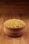 Bulgur in wooden bowl on brown bamboo board, close up. Rustic style, healthy dietary groats background.