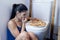 Bulimic woman feeling sick guilty sitting at the floor of the toilet leaning on WC eating pizza