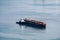 Bulk cargo barge anchors with a tugboat mooring at its side. Bulk cargo is commodity cargo that is transported material in either