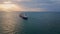 Bulk carrier ship sailing to sunset. Drone view vessel floating in dark ocean.