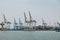 Bulk carrier ship under load of clinker cargo loading by shore cranes with grabs. Sea trading port activity. Bulk cargo