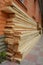 A bulk of solid pine wood boards and planks for solid wood flooring near a brick house